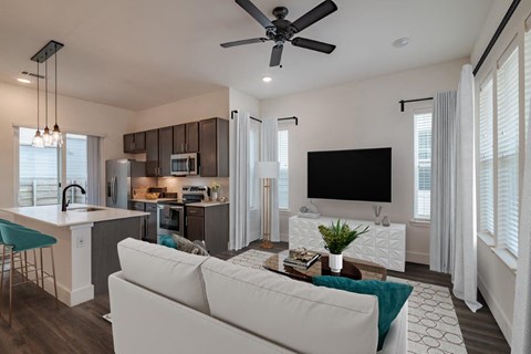 a living room and kitchen with a couch and a tv